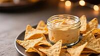 A plate of tortilla chips around a glass of creamy cheese sauce, in warm light, delicious dip, perfect as a side dish for meals and parties, AI generates, AI generated [IBR124458880]