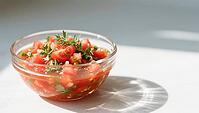 A fresh tomato salad in a glass bowl is illuminated by bright sunlight, hearty party salad, beautifully presented in a glass, AI generated [IBR124458884]