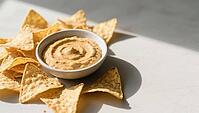 Tortilla chips arranged around a bowl of creamy dip on a table with light-shadow contrast, delicious dip, perfect as a side dish for meals and parties, AI generates, AI generated [IBR124458890]