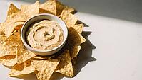 Yellowish dip in a bowl surrounded by tortilla chips in sunlight, delicious dip, perfect as a side dish for meals and parties, AI generates, AI generated [IBR124458902]