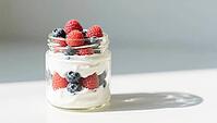 A glass with yogurt and fresh berries in the sun that casts a shadow on a white surface, delicious dessert, beautifully presented, generated by AI, AI generated [IBR124458906]