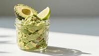 Guacamole in a glass container, decorated with fresh avocado and lime wedges in bright light, delicious dip, perfect as a side dish for meals and parties, AI generates, AI generated [IBR124458911]