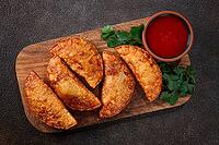 Fried mini chebureks, close-up, on a wooden chopping board, dark background, no people [IBR124476265]