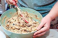 A person is mixing fruitcake batter in a large, turquoise bowl with a red spatula, ready to bake a delicious cake [IBR124491537]