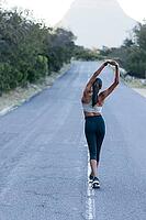 Full length slim female walking on an abandoned road and warming up her body before an outdoor workout [IBR124491541]