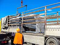 Two workers load large condenser units onto a flatbed truck, securing them for transportation on a bright, sunny day [IBR124491554]