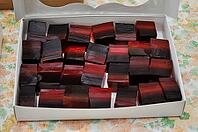 A box filled with colorful, layered square candies, showcasing a unique blend of red and black hues, perfect for dessert [IBR124491561]