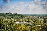 A scenic view of a town with a golden-domed church on a hilltop, under a blue sky with fluffy clouds [IBR124491571]