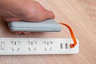 A hand plugging a portable power bank into a power strip. Modern tech to charge electronics [IBR124491589]