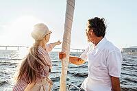 Rearview of two mature people sitting on a sailboat bow and enjoying summer day [IBR124491592]