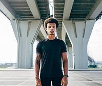 Young man in black sports clothes standing under a highway [IBR124491593]