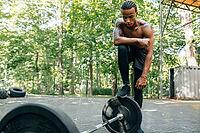 Young sportsman resting after a workout. Bare-chested man standing at the barbell [IBR124491595]