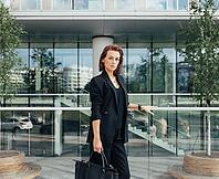 Serious and confident middle-aged woman wearing formal black clothes standing against a modern business building [IBR124491621]