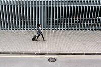 High angle view of businesswoman walking with suitcase near parking garage [IBR124491623]