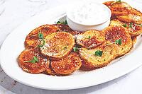 Crispy potato slices, with parmesan cheese and spices, baked in the oven, with zajiki sauce, on a white plate [IBR124491628]