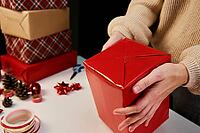 Woman in warm sweater packaging gift box with craft paper. Present for holiday event. Surprise for christmas party [IBR124497435]