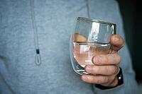 Man drinks water, Close-up shot of man holding glass of fresh water, Quenching thirst, Lifestyle healthcare concept [IBR124497436]