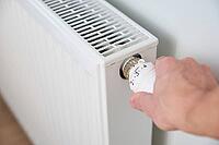 Hand adjusting temperature on heating radiator thermostat, Turning heat radiator knob to control heat in home [IBR124497442]