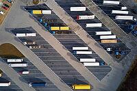 Top view of semi trucks waiting for loading at parking lot at logistic warehouse. Aerial view of highway lorry trailers on rest area [IBR124497445]