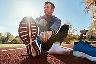 Male runner in blue sneakers get ready for run at stadium track, close up. Male hands tying on sport sneakers for jogging. Fitness and healthy lifestyle concept [IBR124497467]
