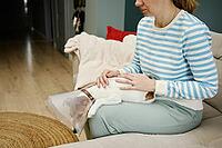 Woman strokes dog wearing medical plastic collar at home. Female owner care about cute dog in Elizabethan collar. Sad Jack Russell Terrier in pet cone in rehabilitation after medical treatment [IBR124497471]