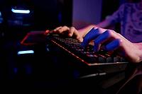 Professional gamer play computer video game in dark room, use neon colored rgb mechanical keyboard, place for cybersport gaming [IBR124497483]