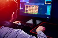 Teenager boy play computer video game in dark room, use neon colored rgb mechanical keyboard, workplace for cybersport gaming, children gaming addiction [IBR124497489]