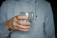 Man drinks water, Close-up shot of man holding glass of fresh water, Quenching thirst, Lifestyle healthcare concept [IBR124497490]