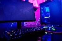 PC with rgb keyboard for gaming computer video games with neon colored background, dark room with game workplace without people [IBR124497495]