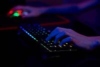 Professional gamer play computer video game in dark room, use neon colored rgb mechanical keyboard, place for cybersport gaming [IBR124497502]