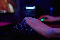 Professional gamer play computer video game in dark room, use neon colored rgb mechanical keyboard, place for cybersport gaming [IBR124497504]