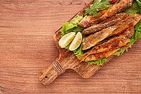 Fried crispy red mullet fish, on a wooden chopping board, with lime, no people [IBR124552169]