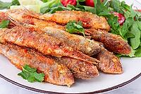 Fried crispy mullet fish, with fresh salad, on a plate with lime, no people [IBR124552180]