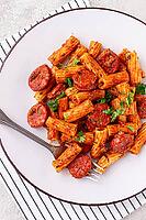 Rigatoni pasta with spicy sausage, and rich tomato sauce served, on a white plate, homemade [IBR124552181]