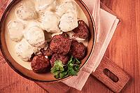 Swedish meatballs in cream sauce, plate on a wooden table, homemade, no people [IBR124552203]