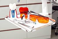 On the tray are various dental instruments, a model dental implant and bright orange safety glasses, ready for use in clinical dental settings [IBR124552206]