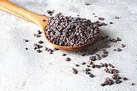 Crystals of black salt, on a wooden spoon, on a light surface, top view [IBR124552207]
