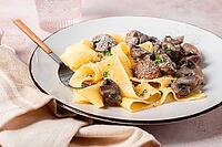 Delicious pappardelle pasta with mushrooms and cream served on a white plate [IBR124552209]