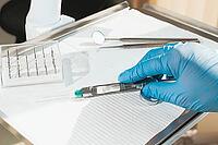 The dentist's hand, in a blue glove, holds a carpal syringe on a tray, ready for a medical procedure [IBR124552220]