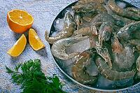 Fresh raw shrimp, spread on ice with lemon and cilantro slices on a marble surface, ready to cook, no people [IBR124552234]