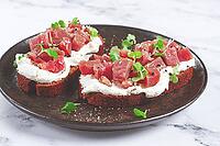Sandwiches, rye bread with cream cheese, sliced tuna fillet with herbs, breakfast on a black plate, homemade [IBR124552241]