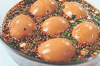 Five soft boiled eggs sit in a bowl filled with soy sauce, chopped green onions, and sesame seeds [IBR124552260]