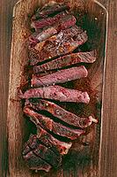 Medium rare, sliced rib eye steak, grilled cowboy steak, on a chopping board, close-up, homemade, top view, no people [IBR124585335]