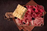 Assorted meat, appetizer, prosciutto, salami and ham, with maasdam cheese and olives, on a wooden board, breakfast, top view, close-up, no people [IBR124585360]