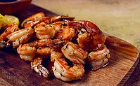Fried tiger prawns, jumbo, in garlic sauce, in butter, with herbs, on a wooden board, homemade, no people [IBR124585368]