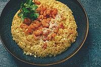 Risotto with shrimp, in a bowl, on a textured surface, with a side dish of fresh coriander, homemade, no people [IBR124585370]