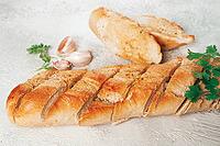 Garlic bread, baguette with garlic butter and herbs, on a light table, top view [IBR124585371]