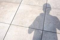 Person's shadow falling on light grey concrete pavement in bright sunlight [IBR124586567]