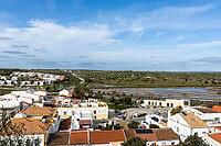 Wide panoramic view of Castro Marim showing traditional white houses with red roofs, streets, and surrounding countryside under a bright sky in the Algarve region of Portugal [IBR124586575]