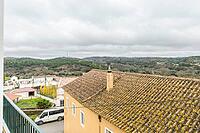 Panoramic view of São Marcos da Serra, a quiet rural village in the Algarve interior of Portugal, featuring traditional white houses, rolling green hills, and a cloudy sky [IBR124586583]